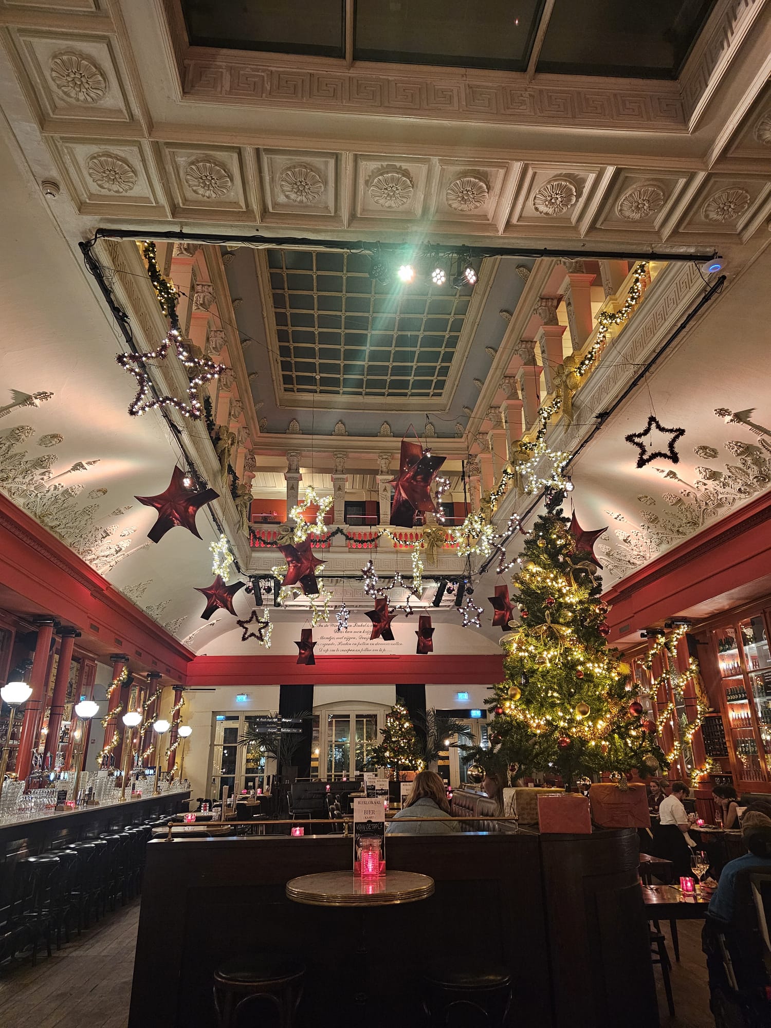 A high-ceilinged atrium decorated for the holidays with a large Christmas tree and hanging star ornaments