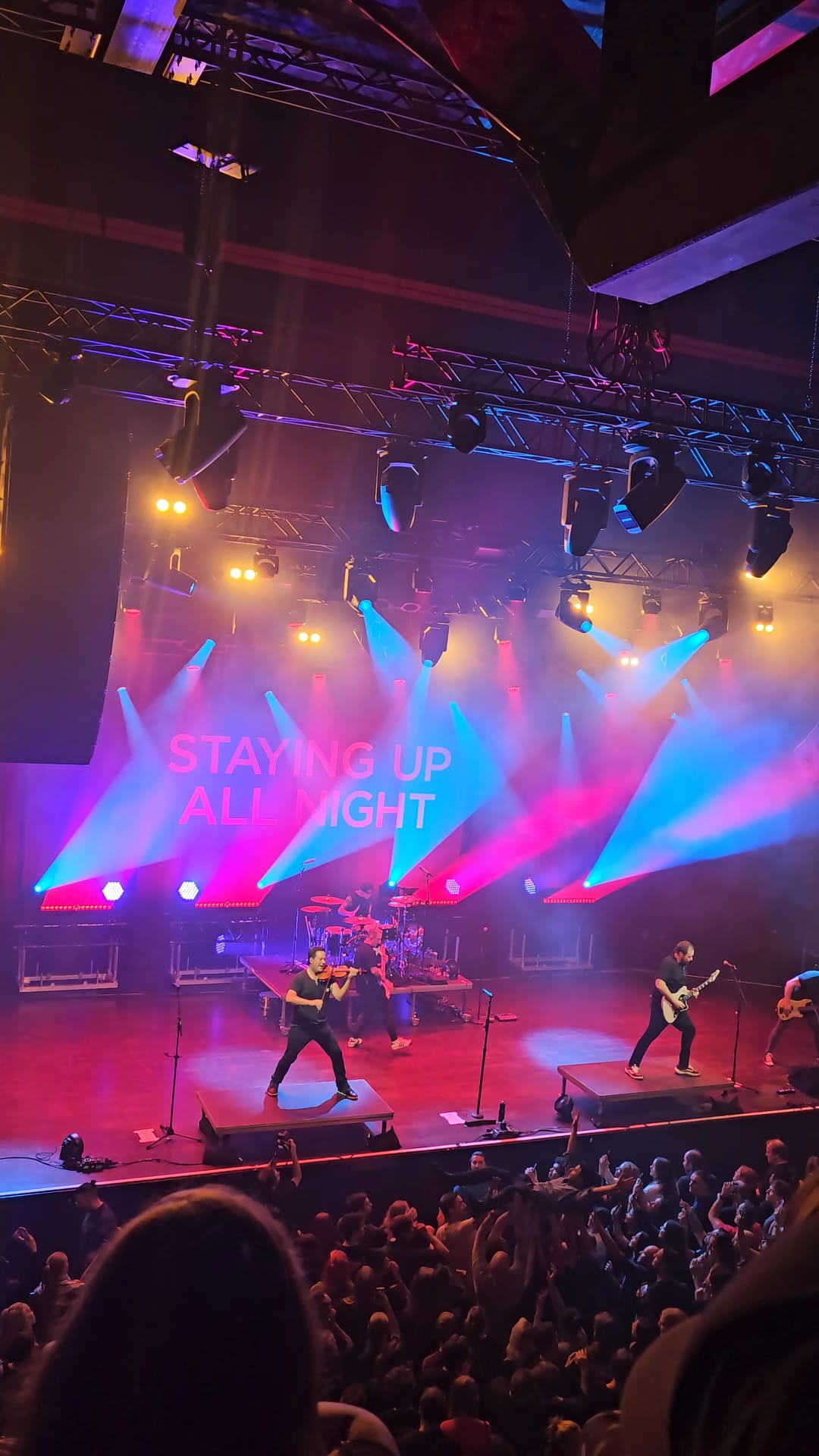 Yellowcard performing on stage with colorful blue and pink lights at Ronda concert venue in Utrecht