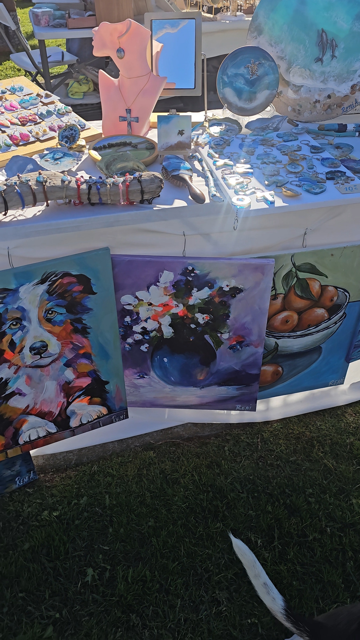 Outdoor art vendor stall displaying colorful paintings and handmade jewelry at Sol de Inverno Festival in Portugal