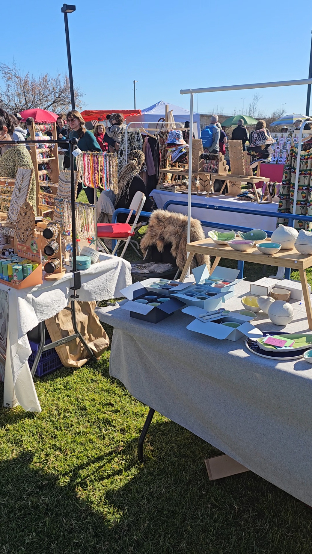 Busy outdoor artisan market with vendors selling jewelry, ceramics, and handmade goods under a clear blue sky at Sol de Inverno Festival in Portugal