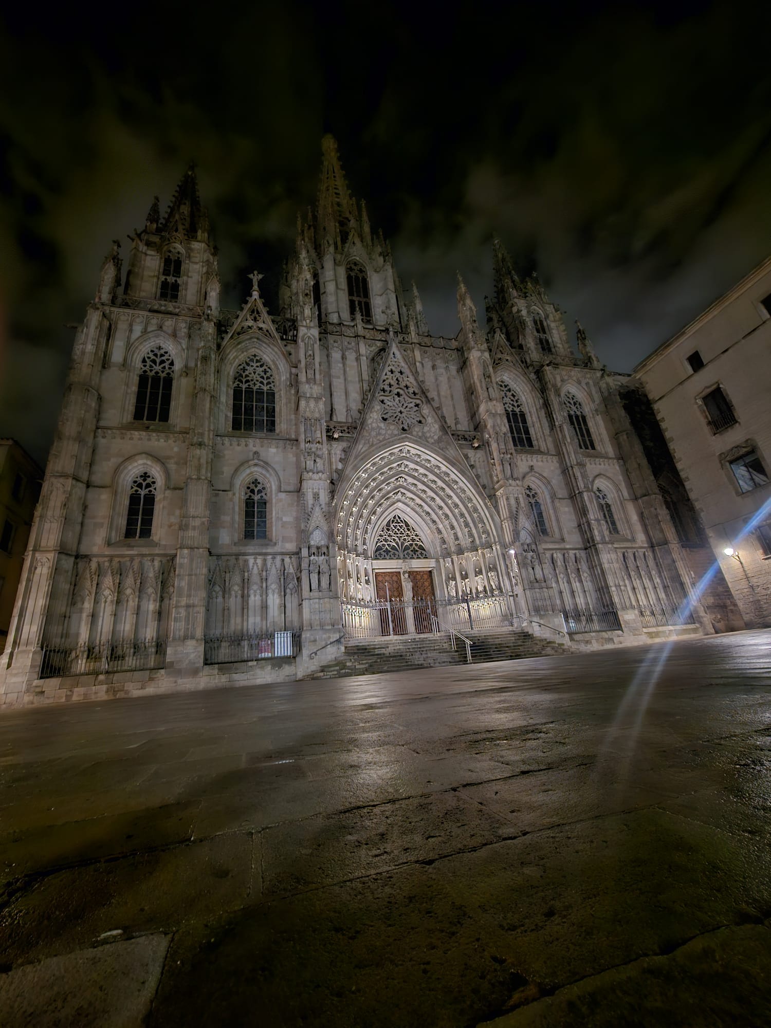 A large, gothic style cathedral with a cloudy night sky behind it