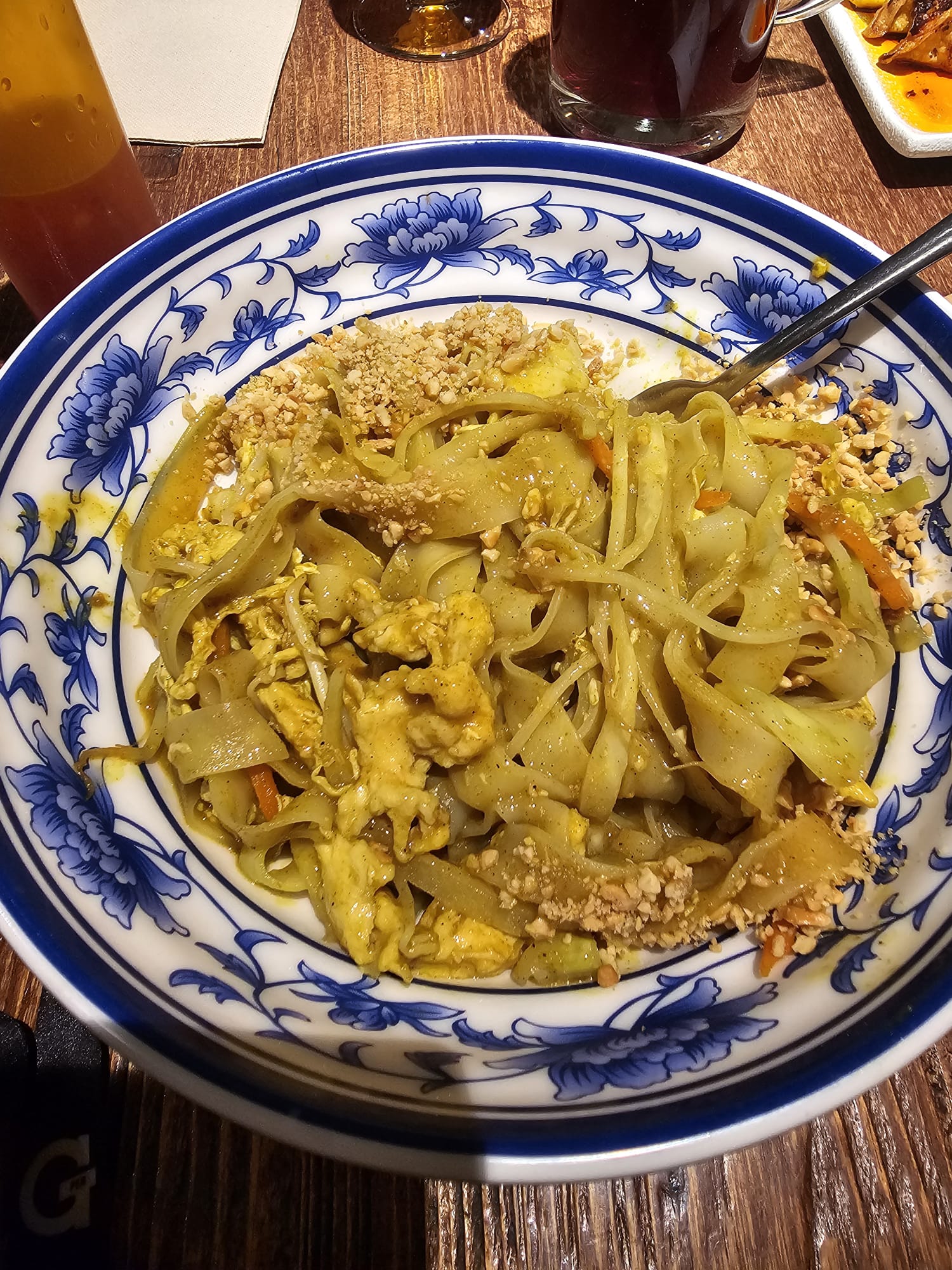 Chicken Pad Thai with flat rice noodles, egg, and crushed peanuts served in a blue and white floral bowl at Pai Mei restaurant