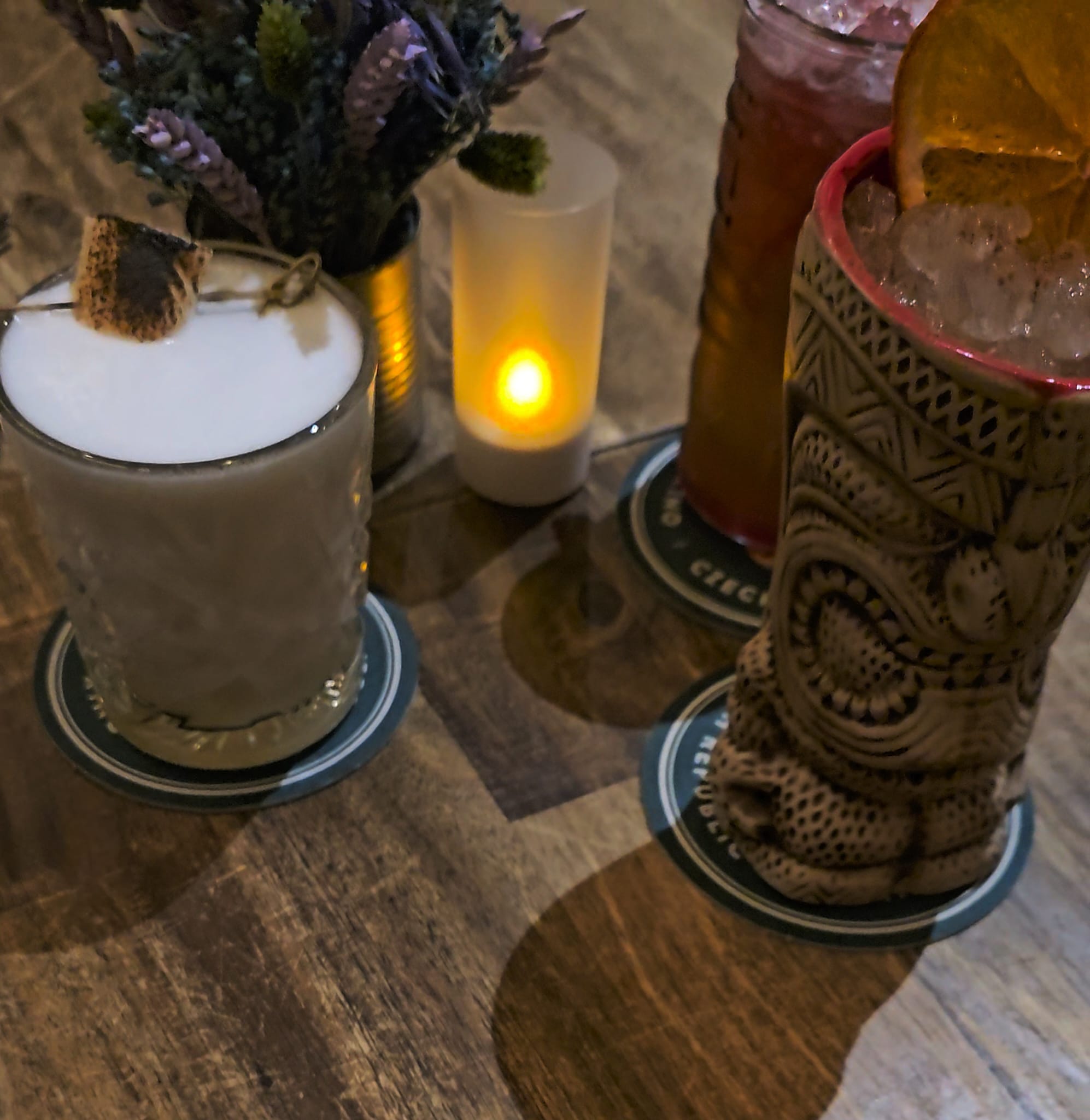 Colorful cocktails and drinks with candles on a wooden table at Kiltro Pisco Restobar