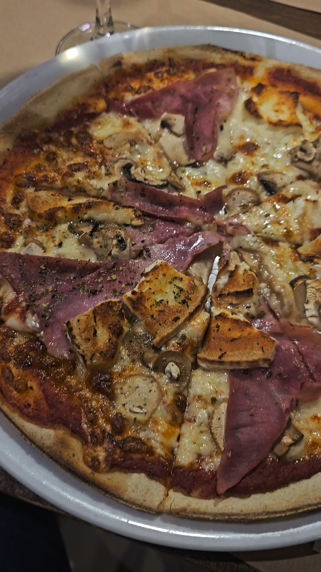 Gluten-free pizza topped with ham and mushrooms in a round metal pan at Messie Pizza