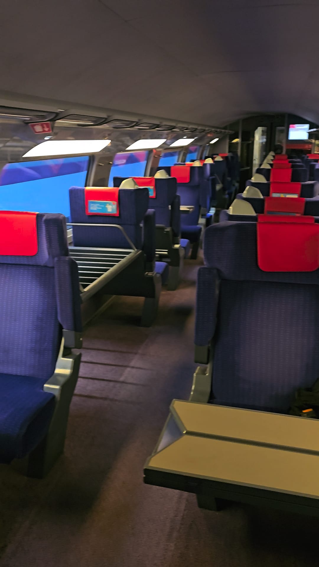 Interior view of a Spanish Ouigo high-speed train car with blue seats and red headrests