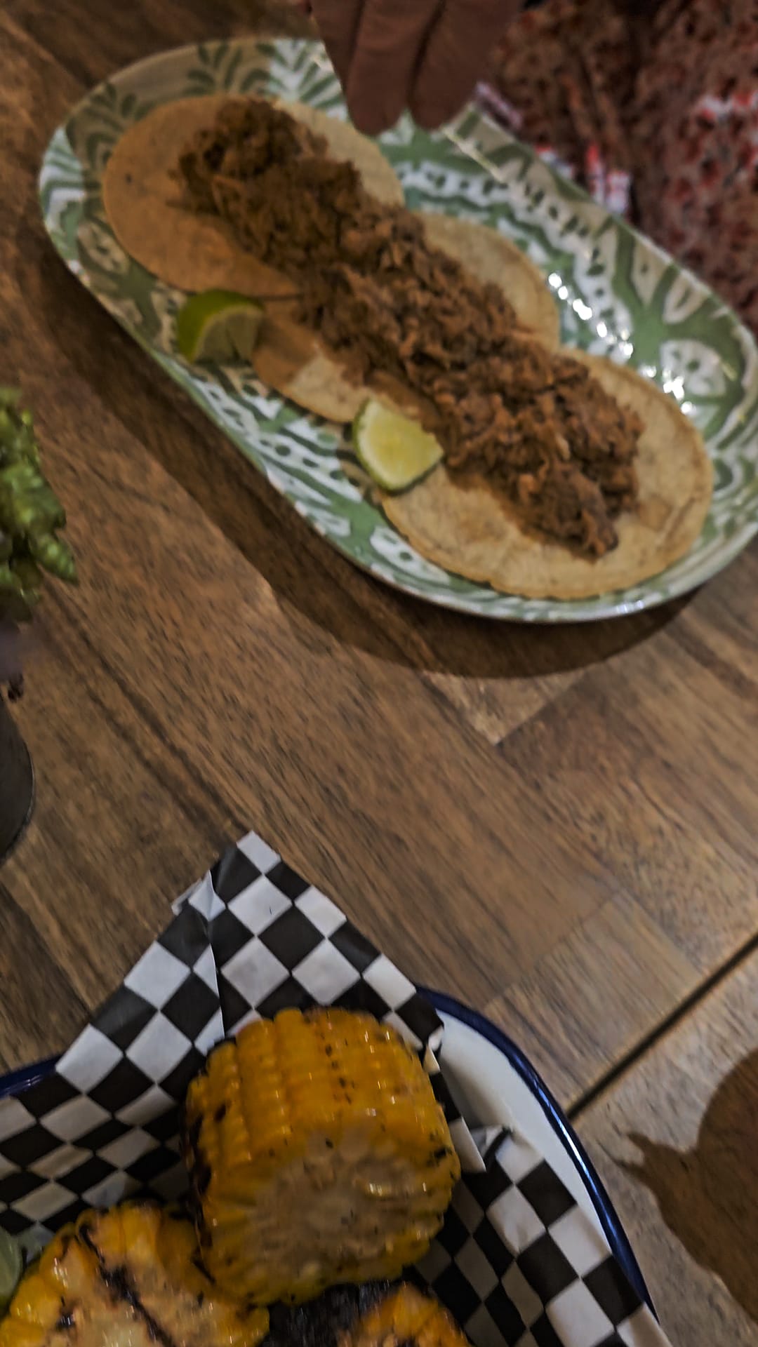 Two gluten-free corn tortilla tacos topped with seasoned ground meat and lime wedges, served on a decorative oval plate at Kiltro Pisco Restobar