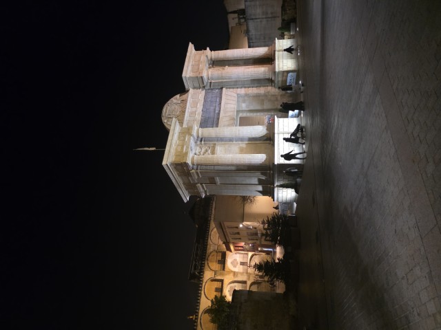 Puerta del Puente city gate in Córdoba Spain lit up at night with people walking in the plaza below