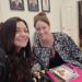Two women smiling at a table with a European Portuguese language textbook during a language class in Portugal