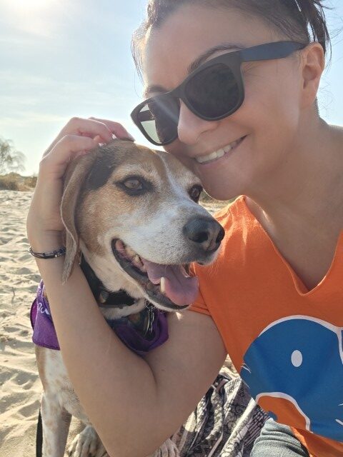 A selfie with a woman and a beagle at the beach 